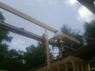 Carpenter setting a ridge beam over a new addition frame — Ice Dam Removal by Roofing Brothers in Ballston Spa