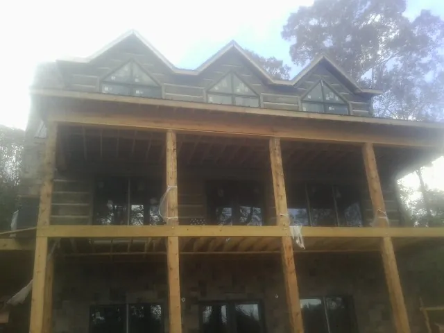 Dormers and porch framing on a large log home under construction — Roof Coating work by our crew in Ballston Spa