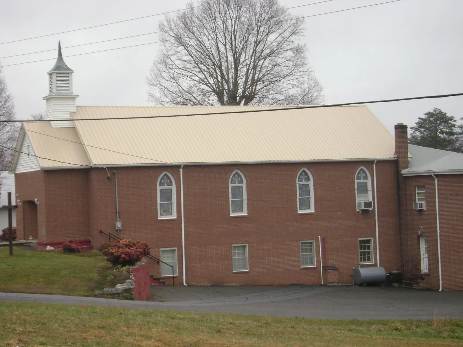 New tan metal roof on a brick church with a white steeple in Ballston Spa