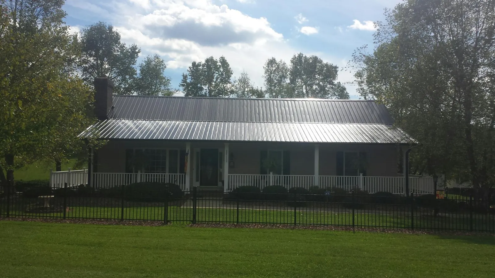 Gray metal roof on a brick ranch with a full width front porch — Gutter Guard Installation work by our crew in Ballston Spa