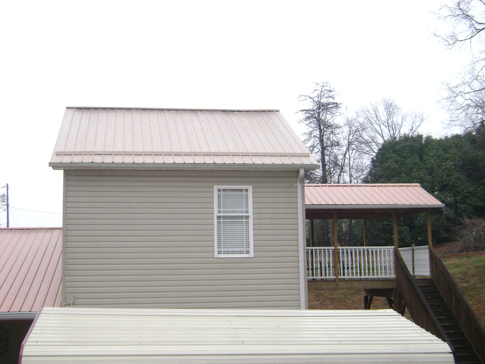 Tan metal roofs on a two story addition and attached porch, from a Roof Replacement job in Ballston Spa