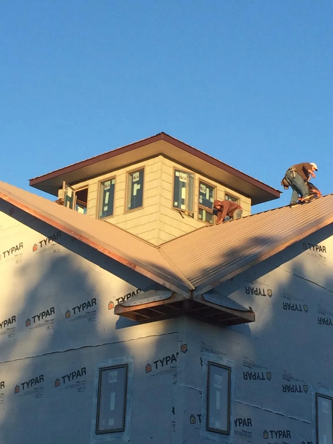 Roofers working around a rooftop cupola on a new metal roof at sunset — Roof Waterproofing in Ballston Spa by Roofing Brothers